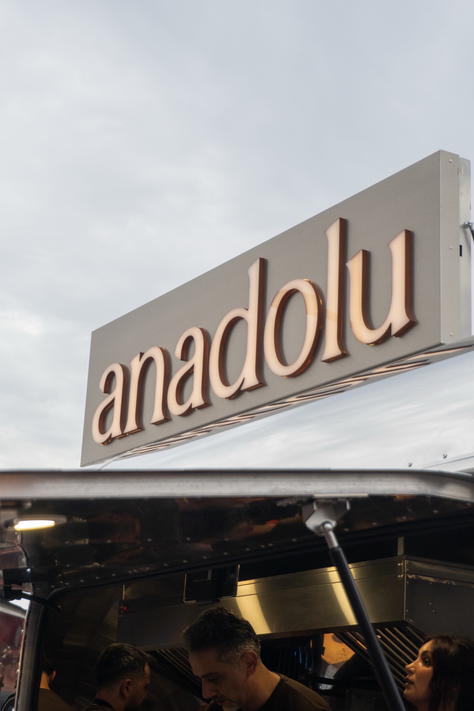 Het verlichte anadolu-uithangbord boven de foodtruck bij het vallen van de avond